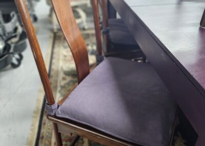 Wooden chair with a padded seat beside a table on a patterned rug.