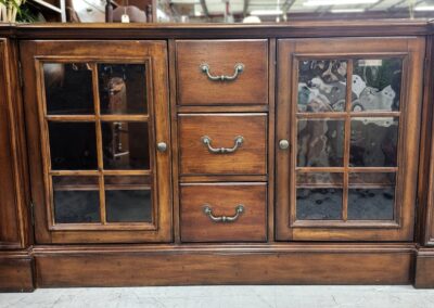 Wooden cabinet with glass-paneled doors and brass handles.