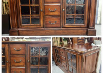 Vintage wooden sideboard with glass-paneled doors and multiple drawers.