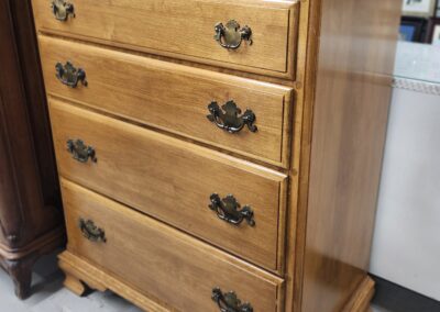 Wooden chest of drawers with ornate handles.