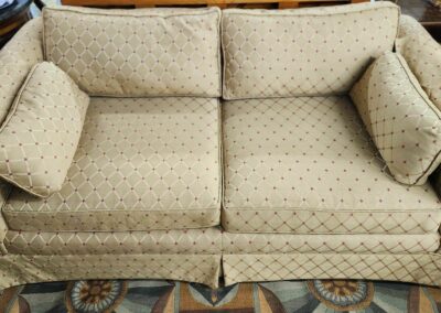 Vintage beige sofa with subtle floral patterns on a colorful rug.