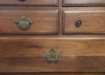 Wooden dresser drawers with antique brass handles.