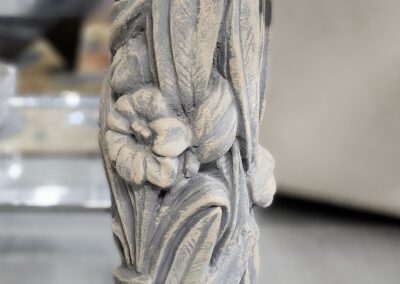 Close-up of an intricately carved wooden furniture leg with floral and leaf designs.