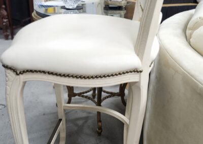 White wooden chair with cushioned seat and nailhead trim.