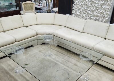 Modern beige sectional sofa with glass coffee tables in a stylish living room.