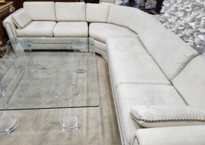 Modern white sectional sofa with glass coffee table in a stylish living room.