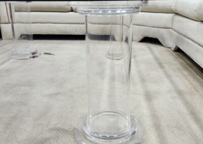 A clear glass vase on a light carpet with a beige sectional sofa in the background.
