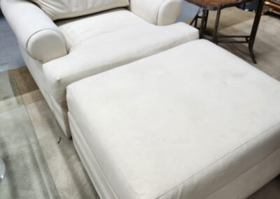 Cream-colored lounge chair with matching ottoman in a cozy room.
