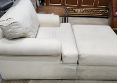 Close-up of a white cushioned sofa with a wooden cabinet in the background.