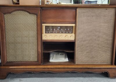 Vintage wooden radio console with built-in speakers and storage compartments.