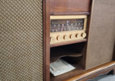 Vintage wooden radio console with fabric speakers and tuning knobs.