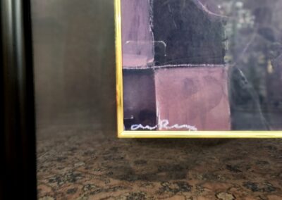 Close-up of a framed abstract artwork with pink and purple tones.
