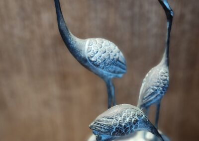 Elegant sculpture of three cranes with long necks and detailed feathers.
