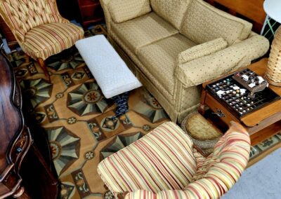 Cozy living room with patterned rug, striped chairs, beige sofa, and a chessboard on a side table.