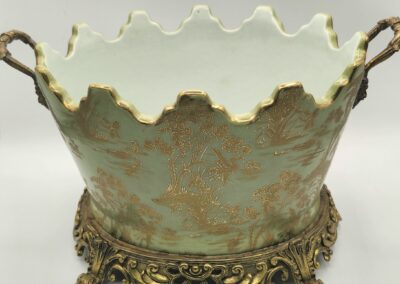 Ornate vintage porcelain bowl with gold handles and intricate base.