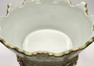Ornate white ceramic bowl with gold-rimmed scalloped edges on a decorative metal base.