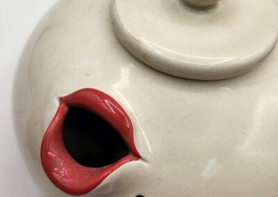 Close-up of a white teapot spout with red interior.
