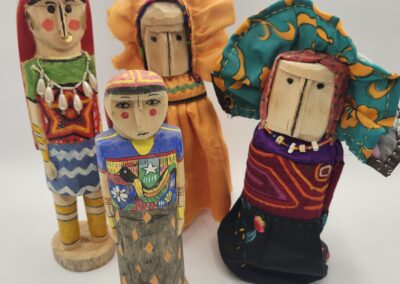 Four colorful handmade wooden dolls with painted faces and clothing.