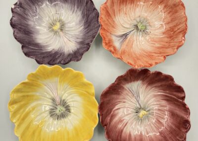 Four colorful, scalloped ceramic bowls arranged in a square.