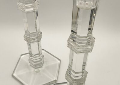 Two clear glass candlesticks with geometric designs on a white background.