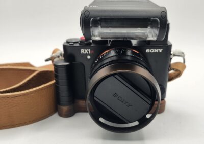 Close-up of a Sony RX1R II camera with lens cap and leather strap.