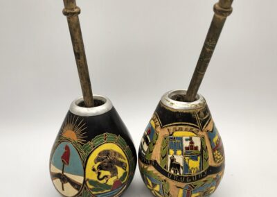 Two decorated metal mate gourds with metal straws.