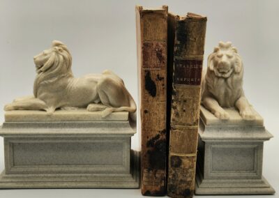Two lion-shaped bookends holding old books upright.