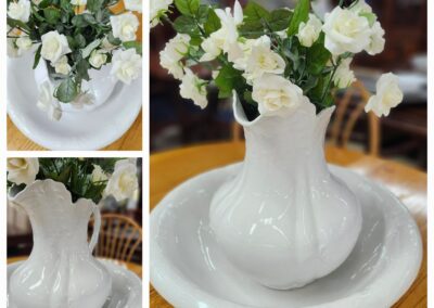 Elegant white ceramic vase with white flowers on a matching plate.