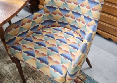 Wooden chair with colorful geometric-patterned upholstery.