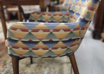 Mid-century chair with colorful geometric upholstery and wooden legs.