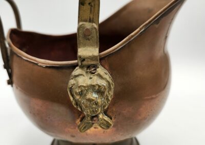 Antique copper vessel with ornate lion head handle detail.