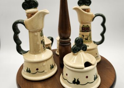 Vintage ceramic cruet set with wooden stand and black handles.