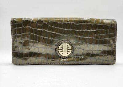 Close-up of a textured brown leather wallet with a gold emblem.