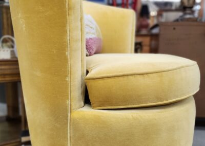 A plush yellow velvet swivel chair with a rounded backrest and cushion.