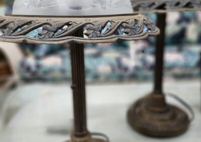 Close-up of a vintage lamp's ornate metal frame and frosted glass shade.