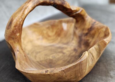 Hand-carved wooden basket with natural grain and handle.