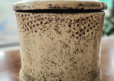 Close-up of a rustic, weathered metal container with a lid.