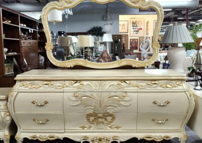 Elegant vintage dresser with ornate gold detailing and matching mirror.