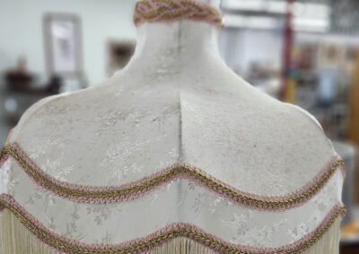 Vintage-style mannequin adorned with decorative fringe and braided trim.
