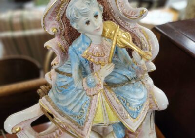 Porcelain figurine of a man in 18th-century attire playing a flute.