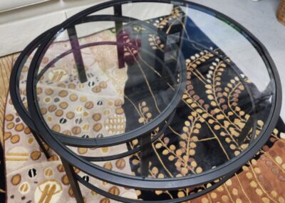 Round glass coffee table with decorative beads on top, placed on a patterned rug.