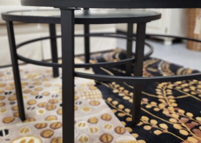 A black metal and glass round table on a patterned tablecloth.