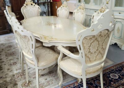 Elegant white dining table set with ornate chairs on a patterned rug.