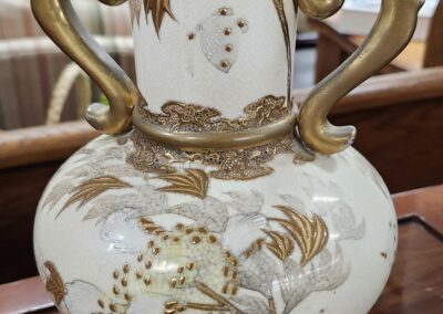 Ornate white ceramic vase with gold floral and butterfly designs and elegant handles.