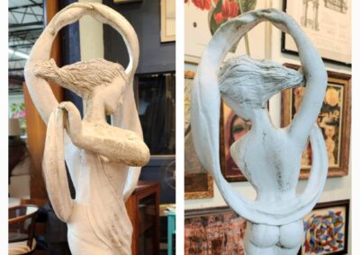 Wooden sculpture of an embracing couple inside an oval frame.