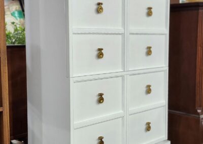 White wooden chest with ten drawers and brass handles.