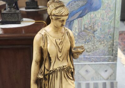 Golden statue of a classical woman holding a cup and pitcher.