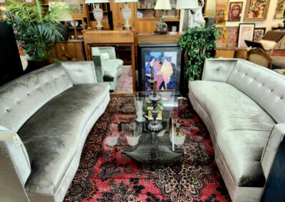 Elegant living room with two velvet sofas and a glass coffee table on a patterned rug.