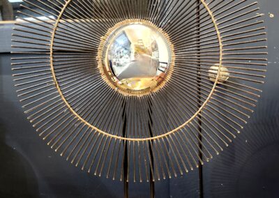 Decorative golden orb sculpture with radiating wire spokes on a stand.