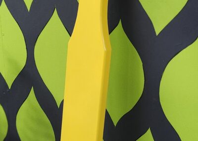 Bright yellow paddle resting on a green and black patterned surface.